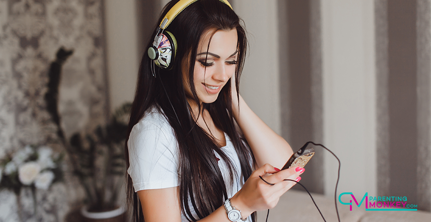 Girl wearing headphones looking at her mobile phone.
