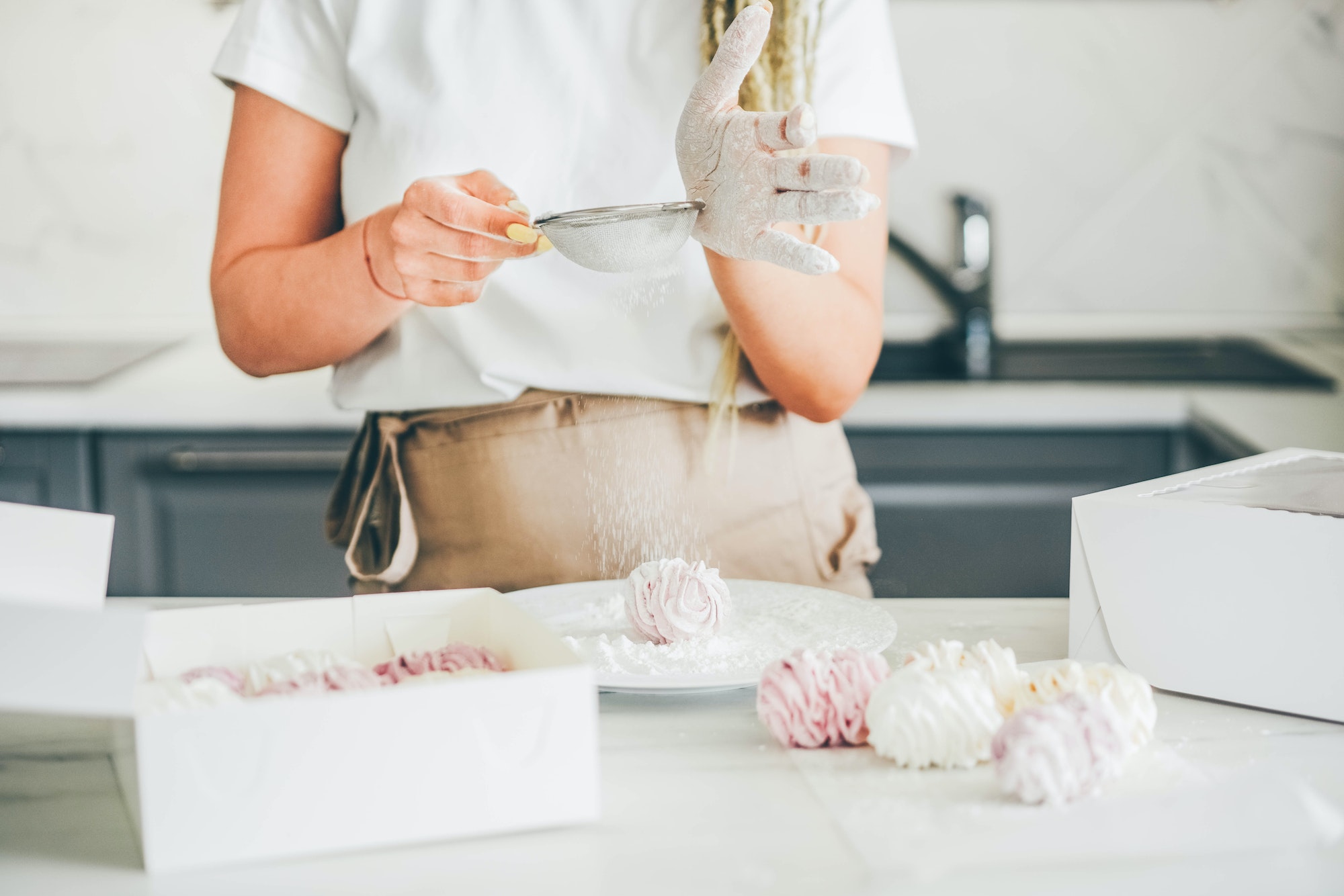 Skilled female confectioner covers delicious homemade multicolored marshmallows