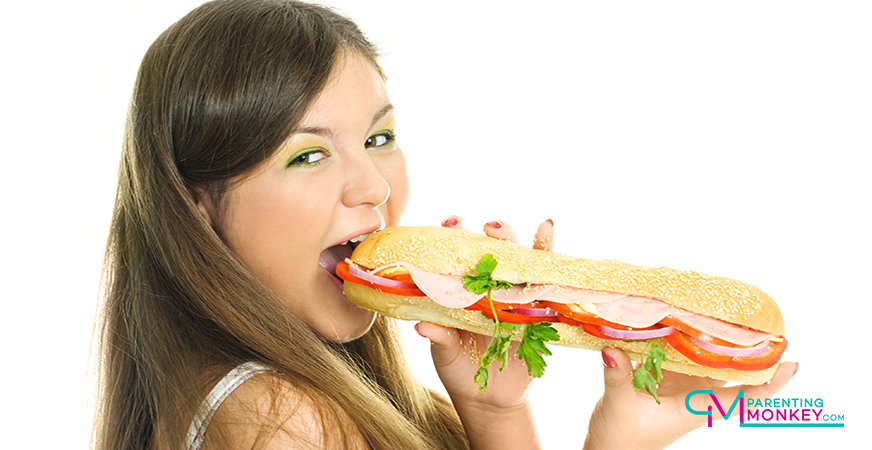 Teenager eating a foot-long sandwich