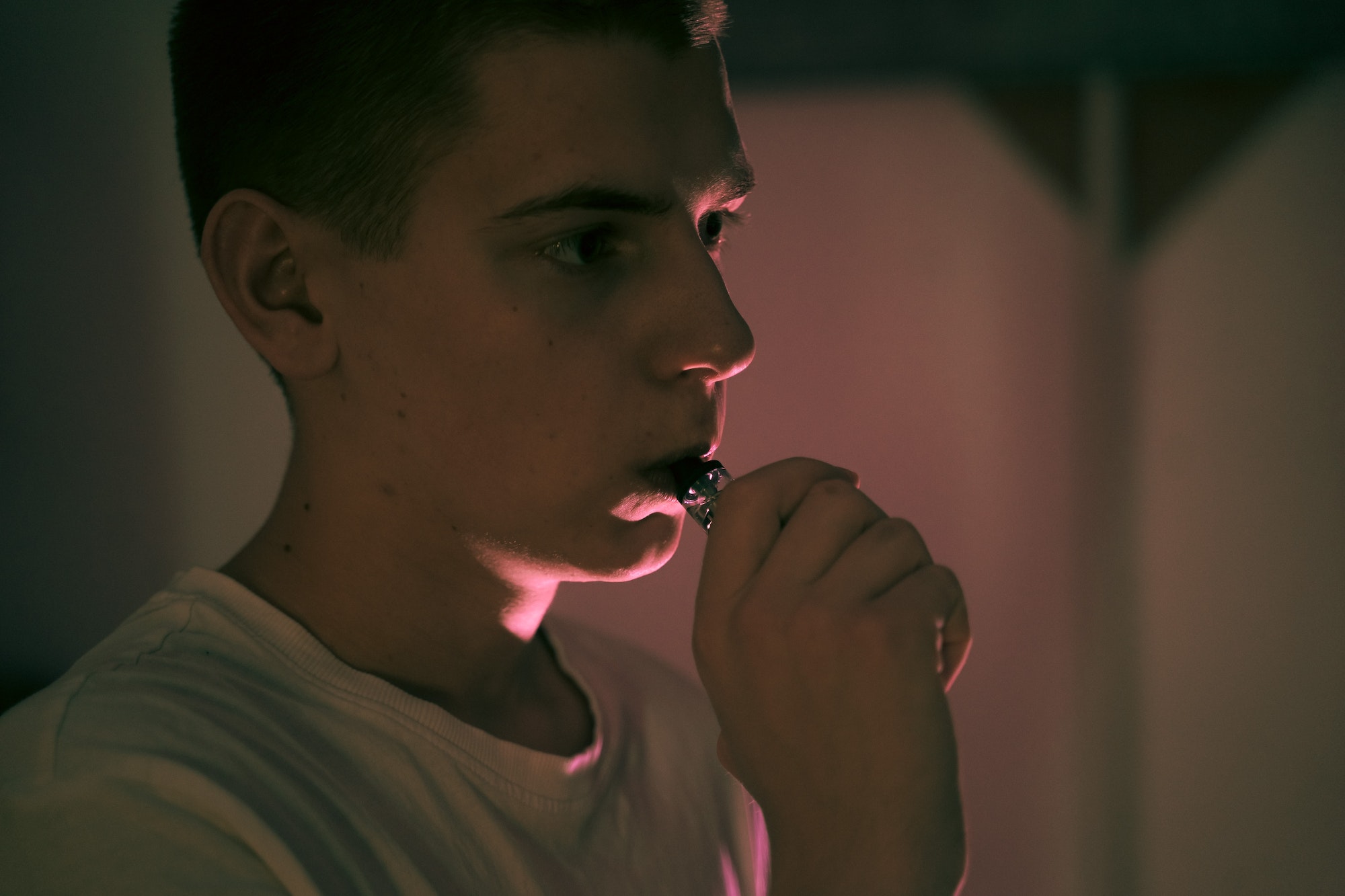 teenager holds a vape in his hand, exhales steam