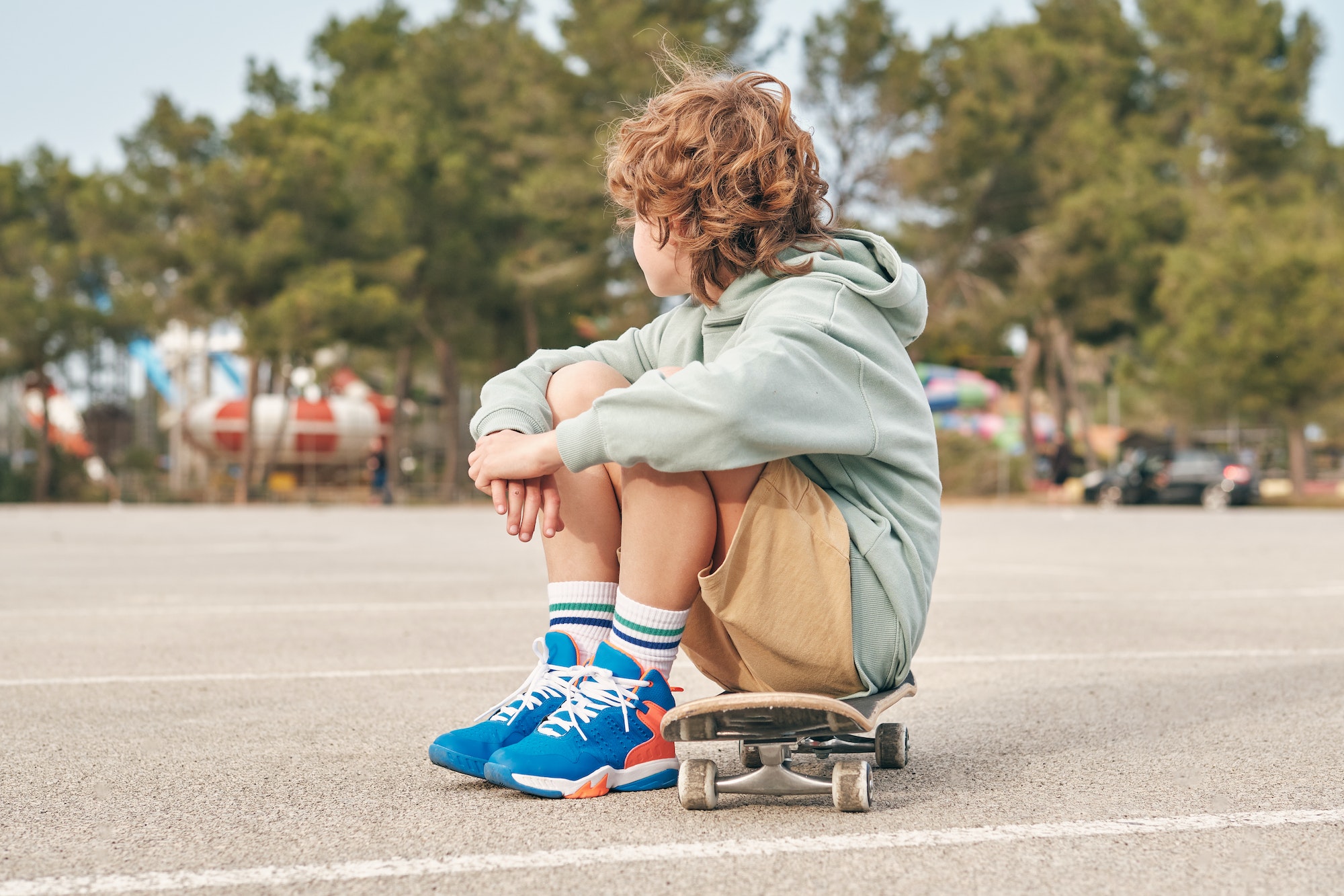 Unrecognizable teenager sitting on skateboard in city